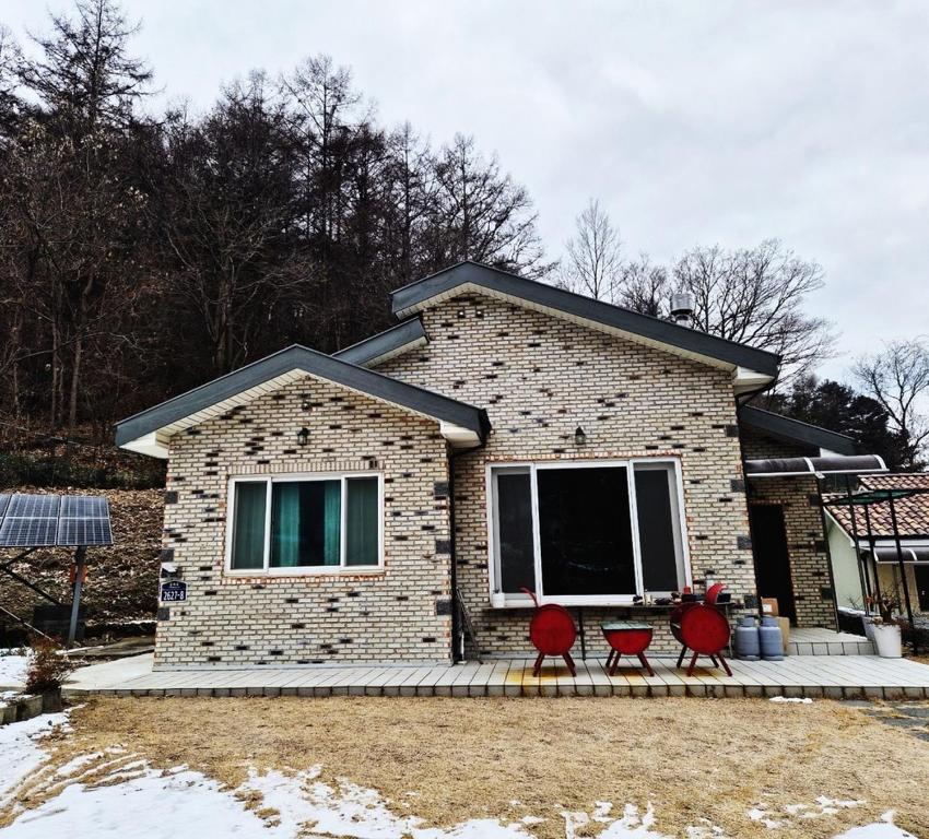 a brick house with three red chairs in front of it at Hwacheon Ujune Minbak in Hwach'ŏn