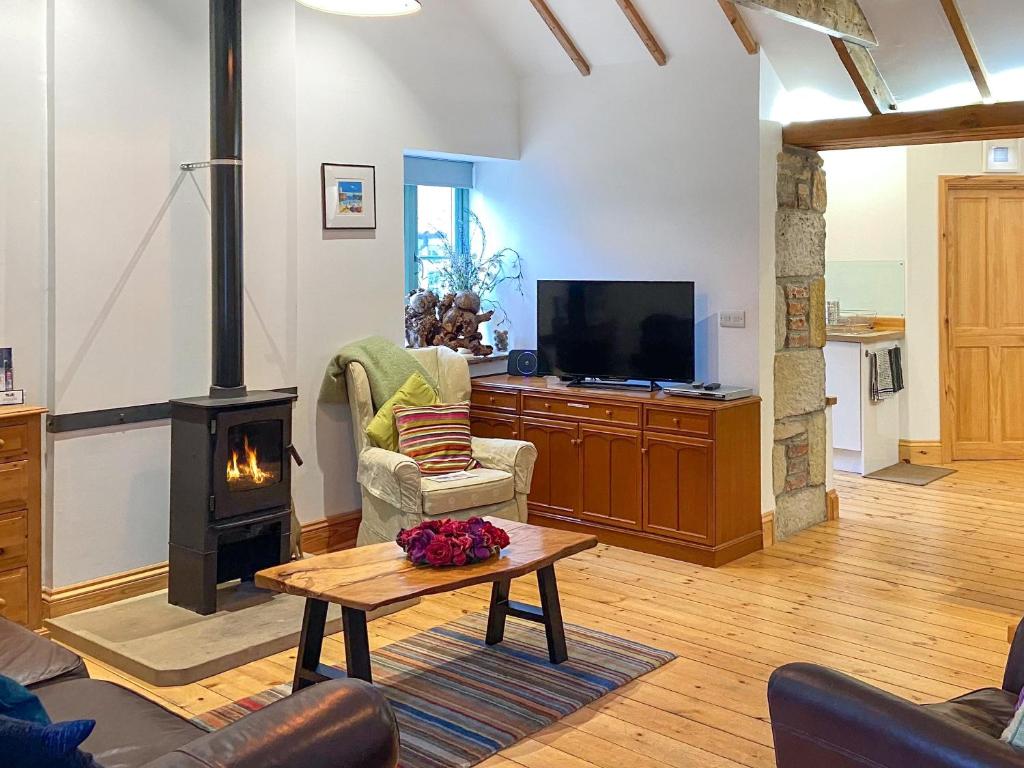 a living room with a fireplace and a tv at No2 The Neuk in Belford