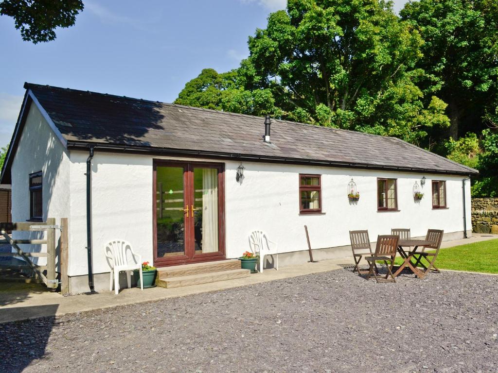 a white cottage with chairs and a table at Tan Rallt Barn in Tregarth