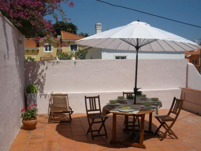 stół i krzesła z parasolem na patio w obiekcie Villa Charme w mieście Estoril