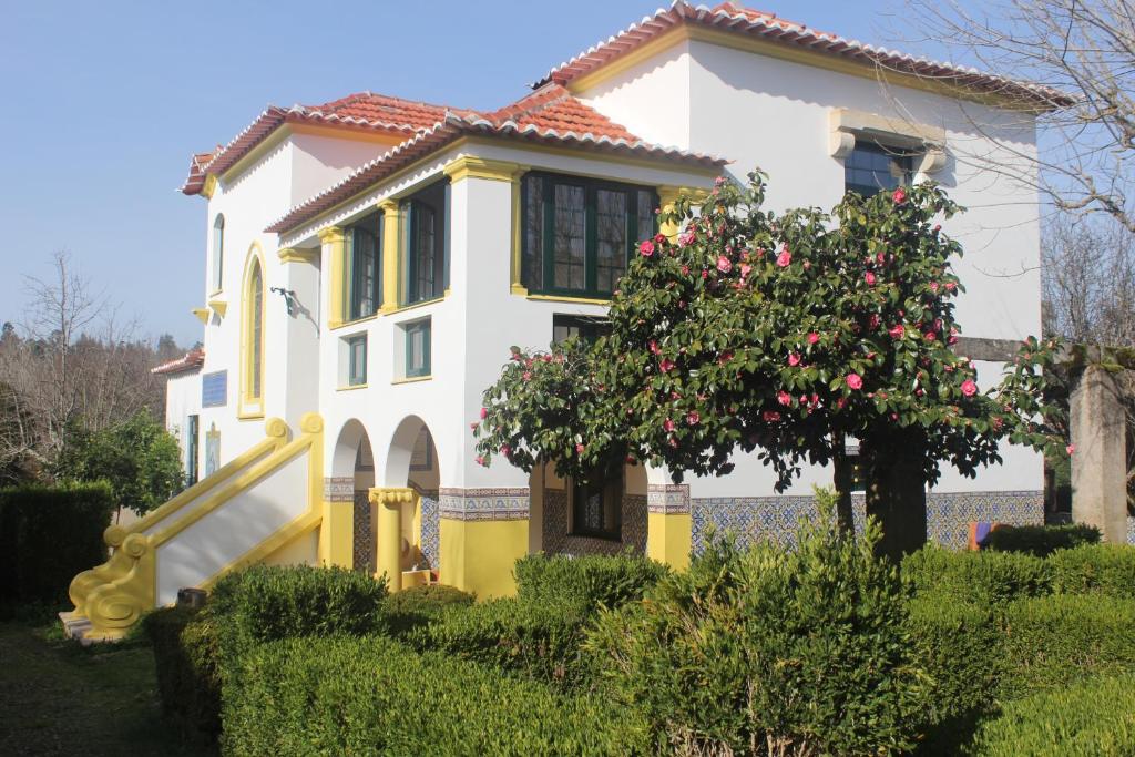 uma casa amarela e branca com uma árvore em frente em B&B Casa das Eiras em Pereira