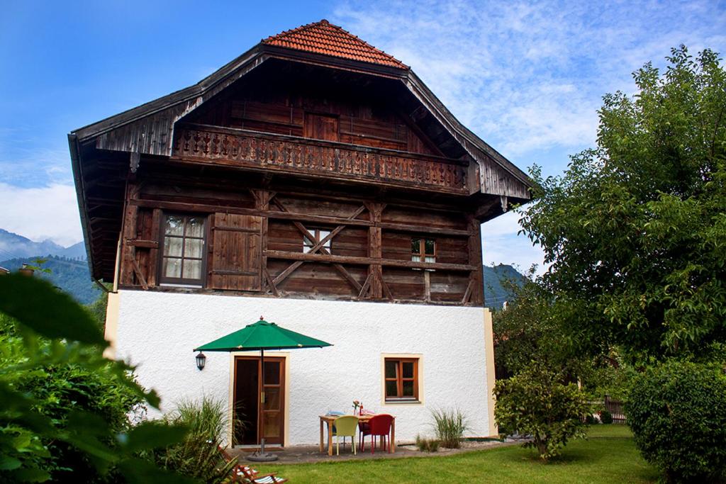 ein Haus mit einem Tisch und einem Sonnenschirm davor in der Unterkunft Haus am Salinenweg in Grassau