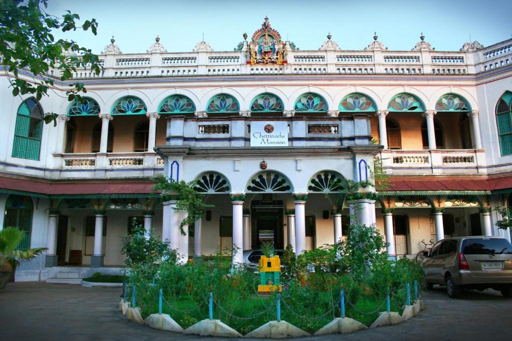 ein großes Gebäude mit einem davor geparkt in der Unterkunft Chettinadu Mansion – An Authentic Heritage Palace in Kānādukāttān