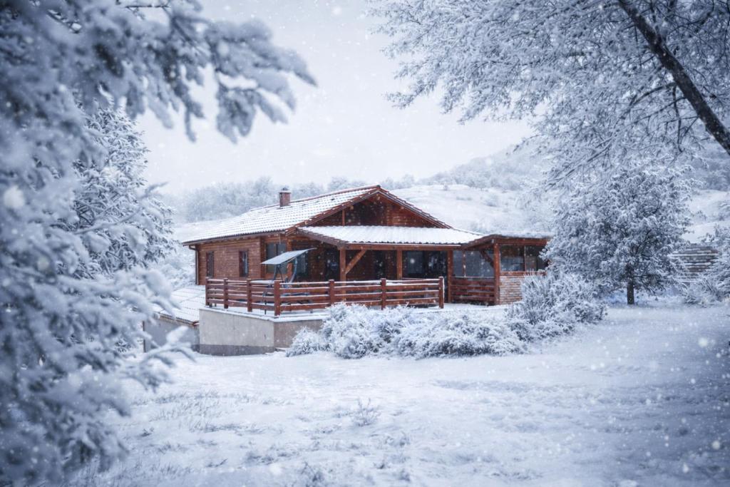 a wooden cabin in the snow with snow covered trees at Bibe Vendégház in Mónosbél