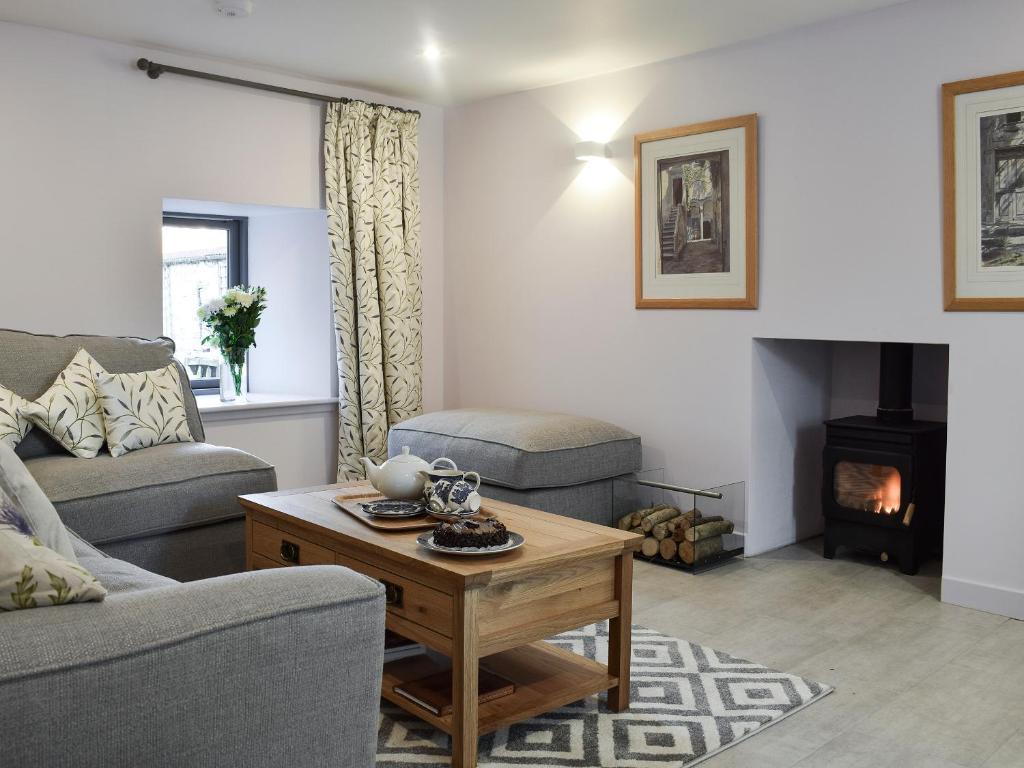 a living room with a couch and a table and a fireplace at Rowanlea in Muthill