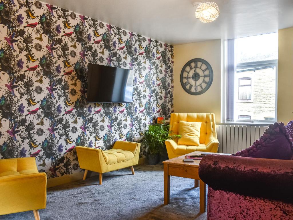 a living room with yellow chairs and a flat screen tv at Hollingreave House in Burnley