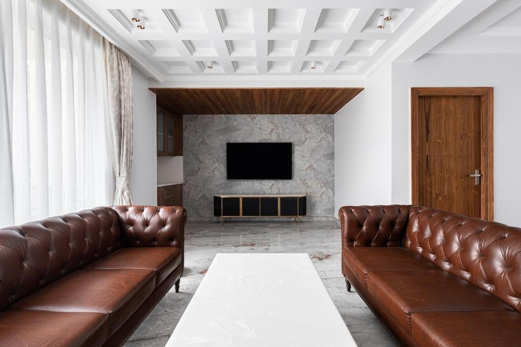 a living room with two brown leather couches and a television at Entire 4bhk villa in Panchkula, Chandigarh in Panchkula
