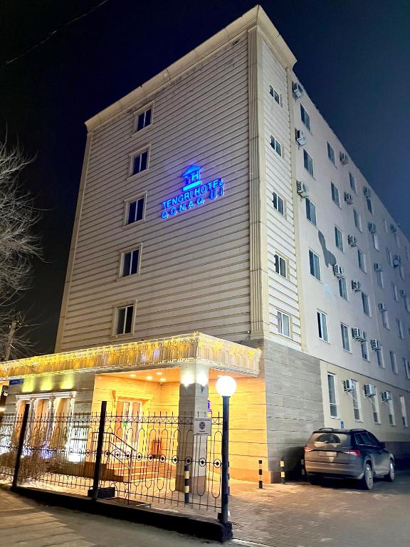 a building with a car parked in front of it at Tengri Hotel in Atyrau