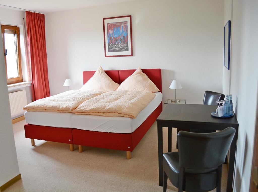 - une chambre avec un lit rouge et blanc et un bureau dans l'établissement Gasthaus Metzgerei Pension Maßem, à Schillingen
