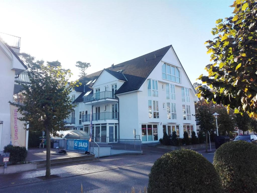 a large white building with a black roof at Fewo Meeresleuchten - Strandkorb auf Balkon, TG in Baabe