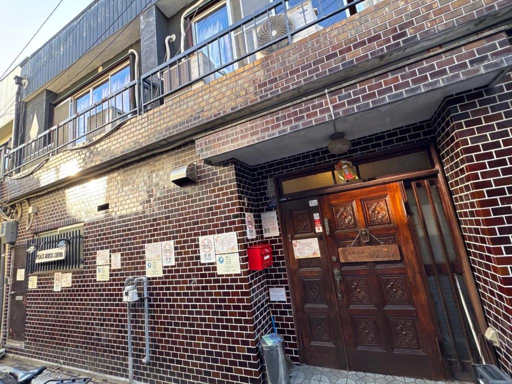 a brick building with two doors and a balcony at Peace House Showa in Osaka