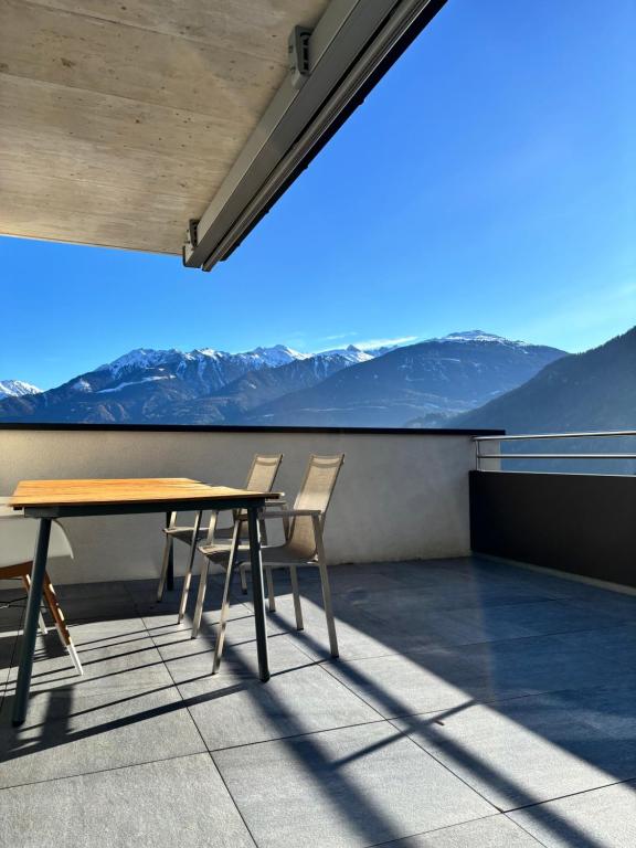 a table and chairs on a balcony with mountains at Panorama Apartment Imst in Imst