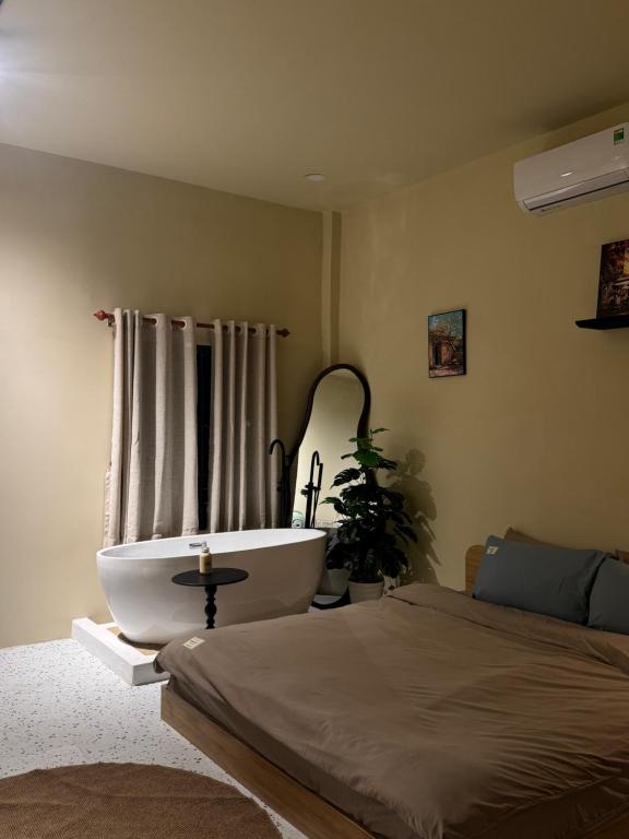 a bedroom with a bath tub next to a bed at Gác Homestay Phan Thiết in Ấp Sung Xuân