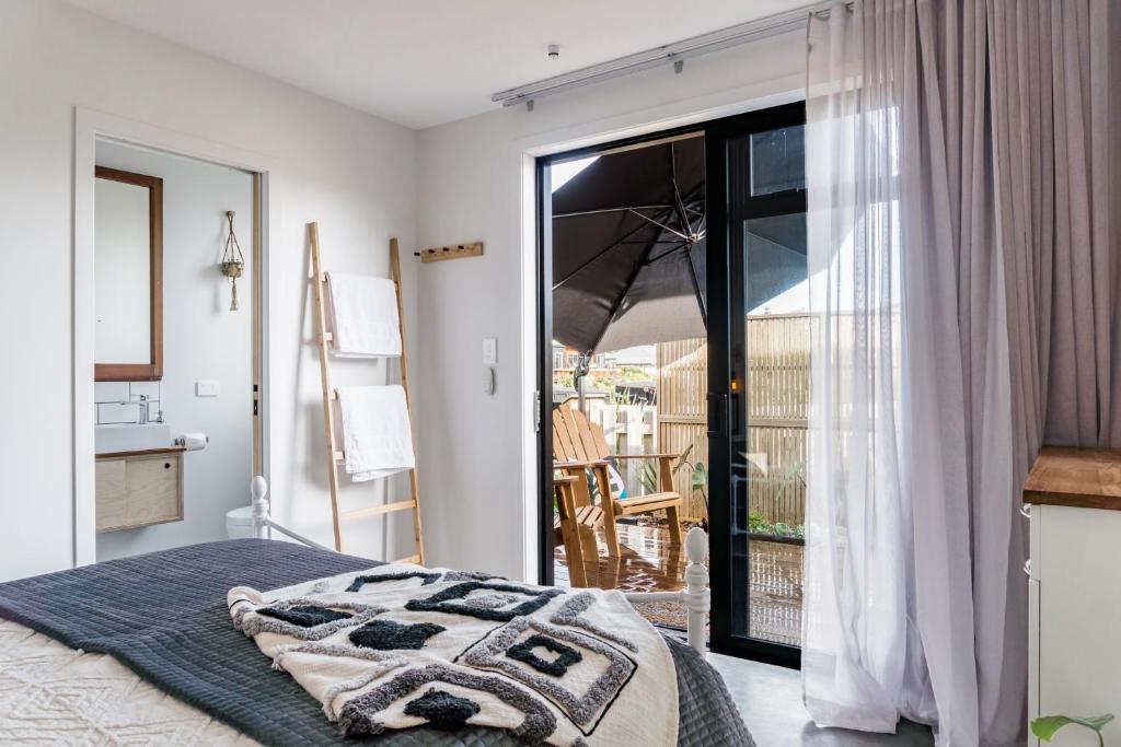 a bedroom with a bed and a door to a balcony at Walnut Studio in Raglan