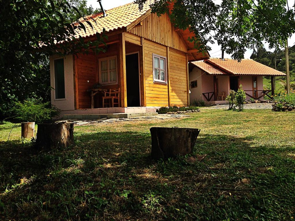 una pequeña casa de madera con dos troncos delante en Café e Cabanas Lenha no Fogo en Urubici