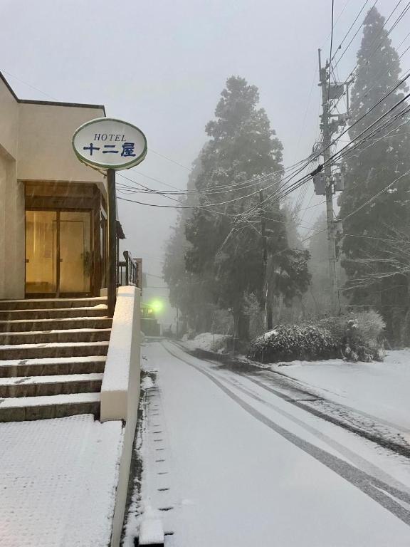 a snow covered street with a train station at Juniya Myoko in Myoko