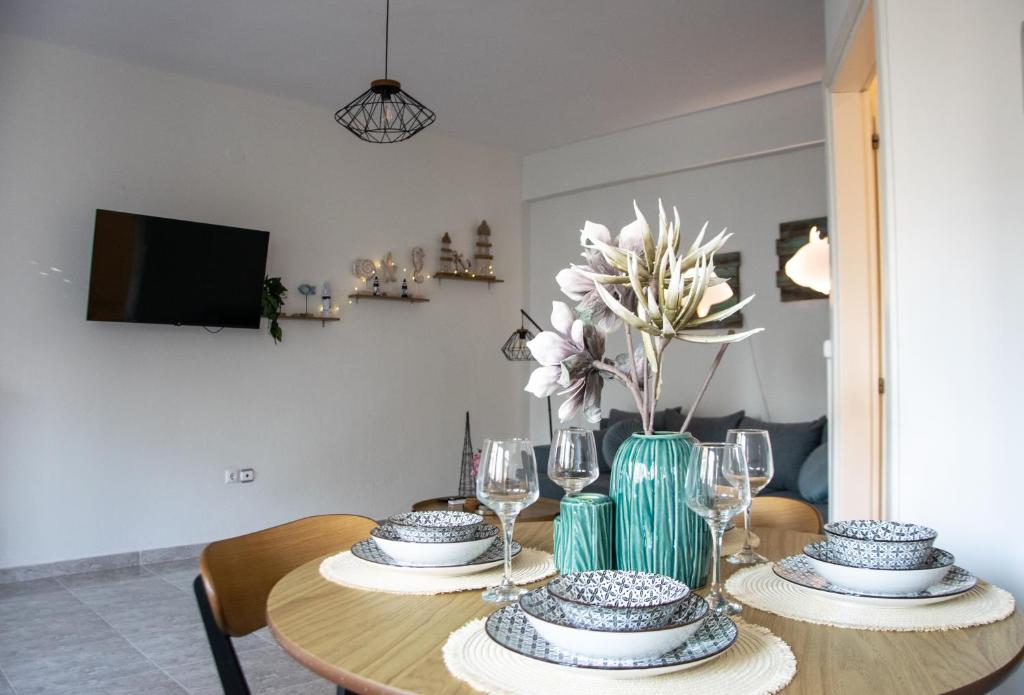 a dining room table with a vase of flowers and glasses at Faros AXD Apartment in Alexandroupoli