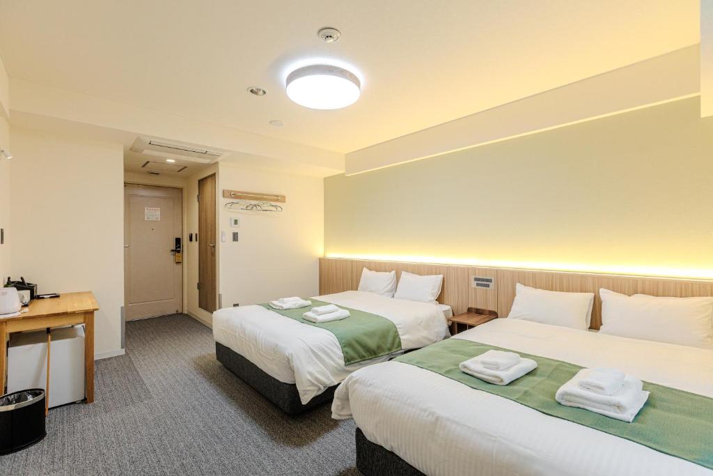 a hotel room with two beds and a desk at アメ村ガーデンホテルAmemura Garden Hotel in Osaka