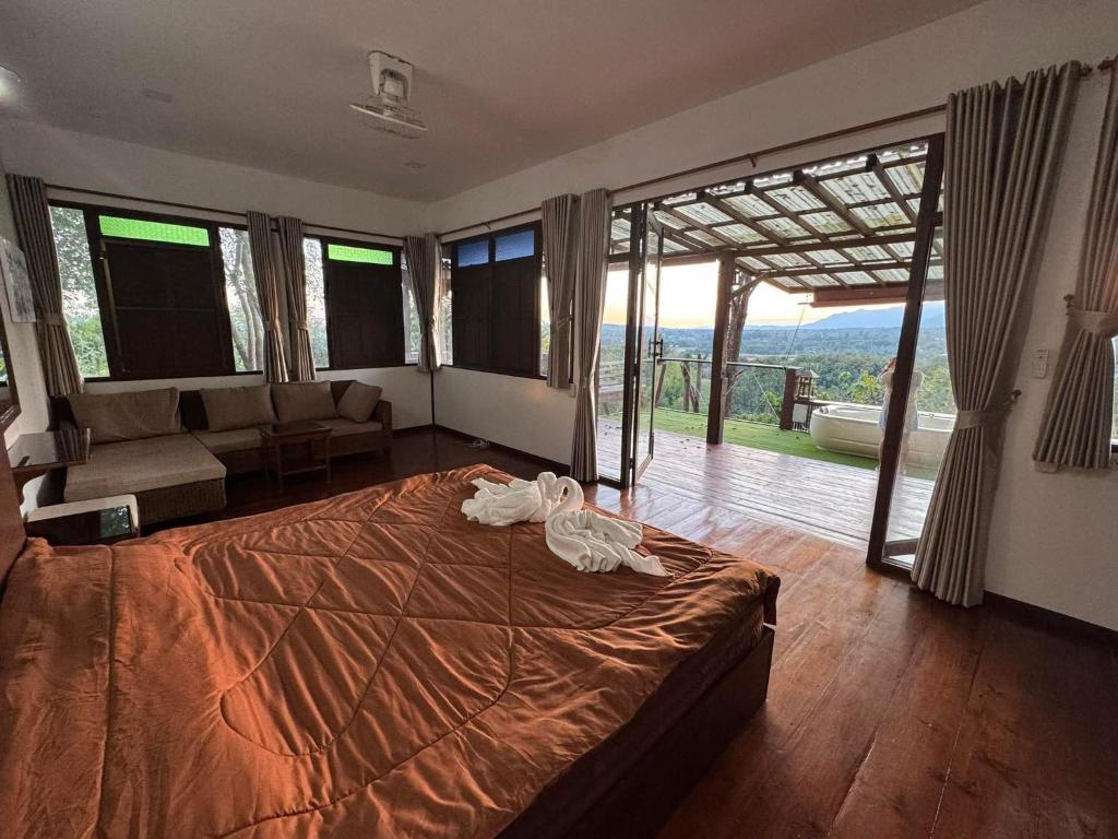 a bedroom with a large bed and a living room at Wanwan Lanna By Pat in Ban Huai Thong