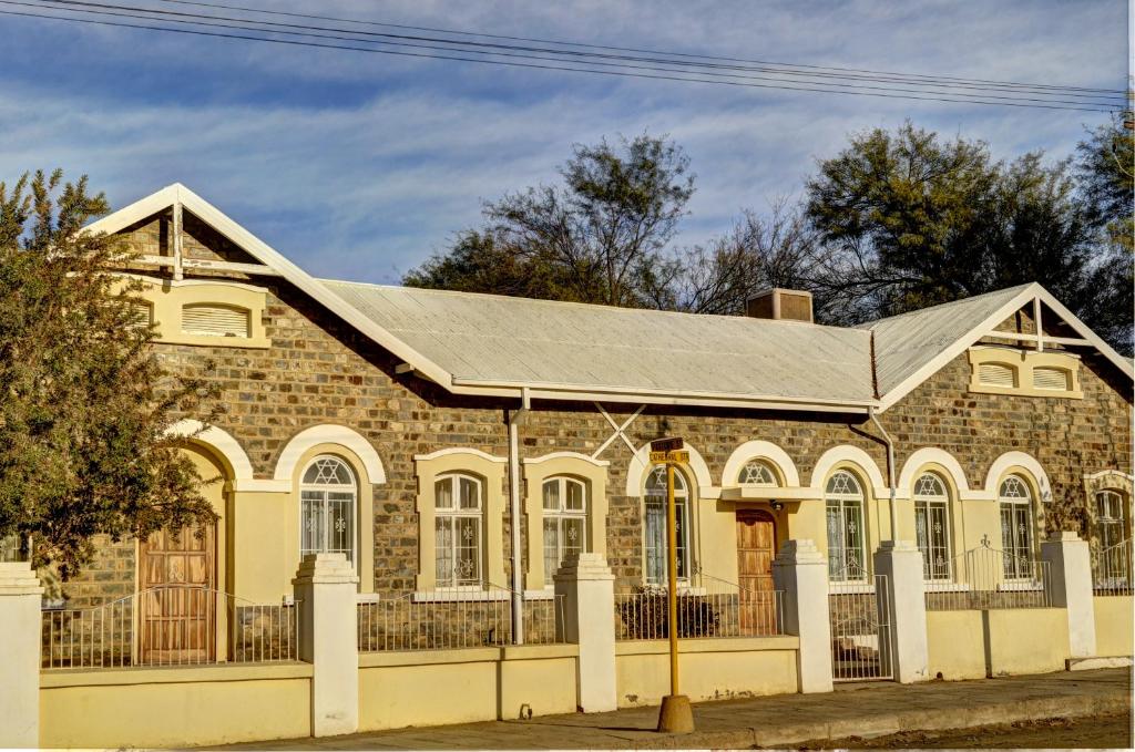 une ancienne maison en briques avec un toit métallique dans l'établissement Schuetzenhaus Guesthouse, à Keetmanshoop