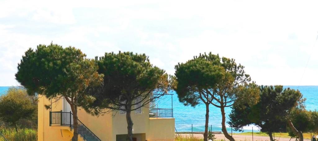 ein Gebäude mit Bäumen vor dem Meer in der Unterkunft Romanos Beach Villas in Romanós