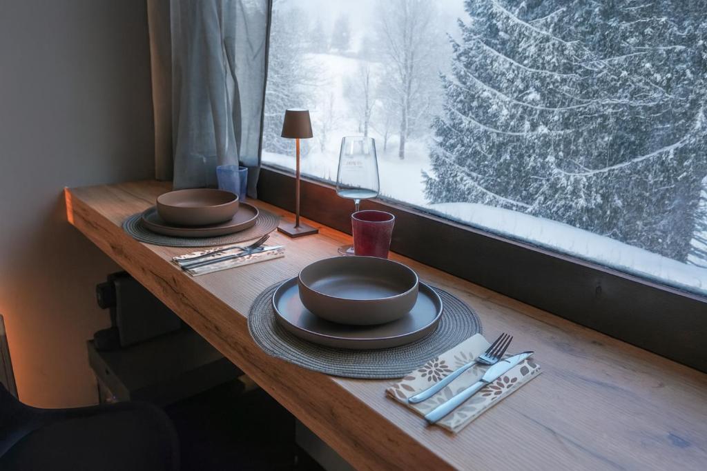 a table with plates and utensils on a table with a window at Sauna Relax in Piancavallo mountain in Piancavallo
