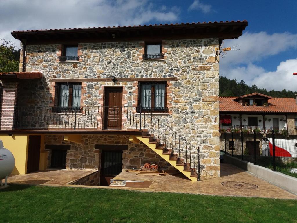 a stone house with a staircase in front of it at La Casuca in Rasines