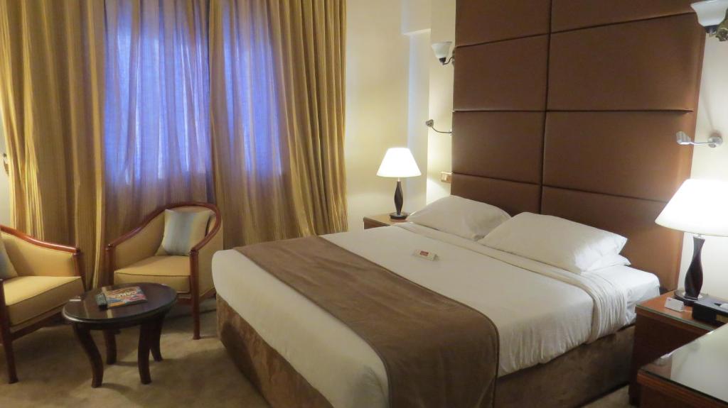 a hotel room with a large bed and a chair at THE PARK HOTEL Formerly Al Jawhara Gardens in Dubai