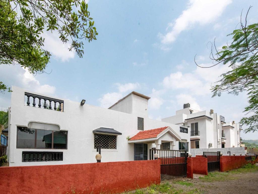 ein weißes Haus mit einem roten Zaun davor in der Unterkunft Palette Mountain Mist Villa | 2BHK | Jacuzzi | Pool | Lonavala in Lonavla
