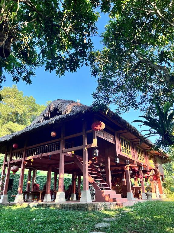 a building with a thatched roof with people in it at Mai's Farm Homestay in Làng Mán