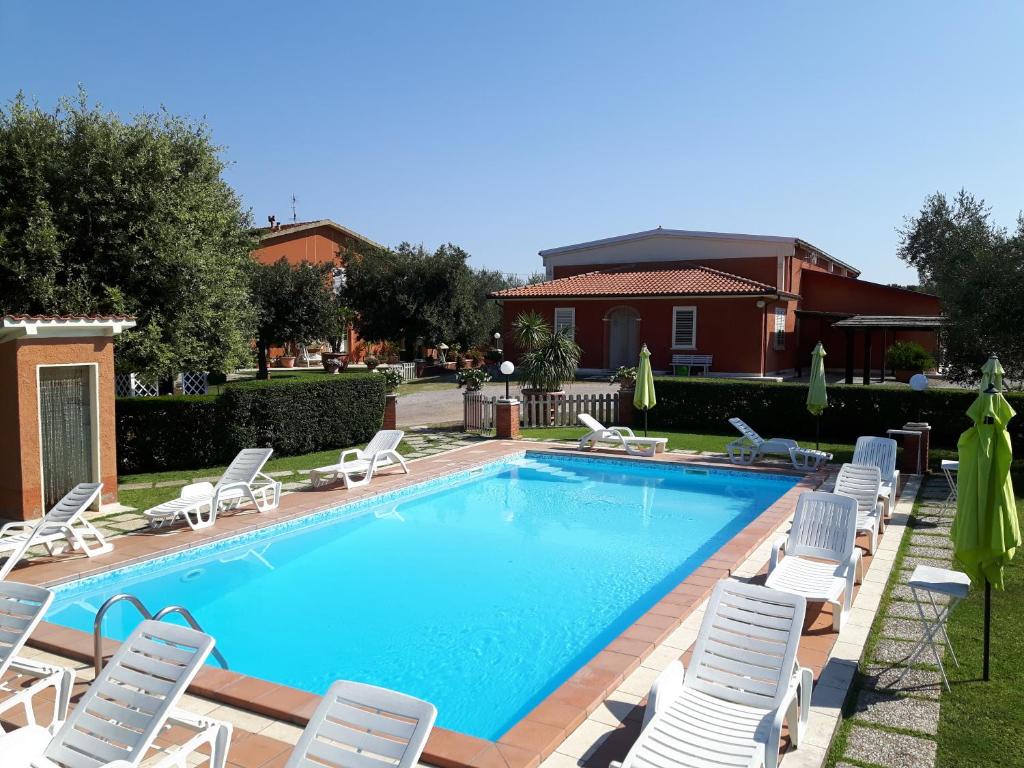 a swimming pool with chaise lounges and chairs around it at Agriturismo Galeazzi in Marsiliana