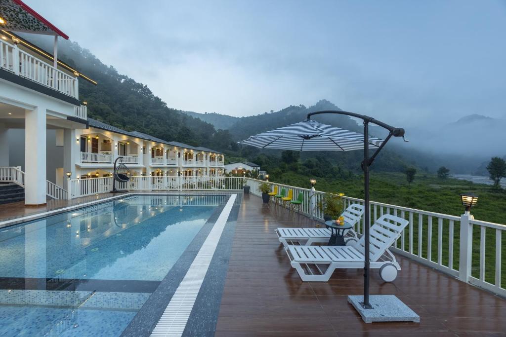 a hotel with a pool and two chairs and an umbrella at PACK Rishikesh, Mohanchatti in Rishīkesh