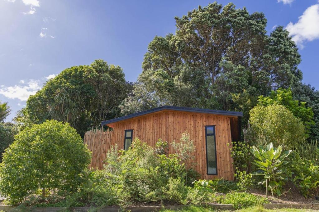 a small wooden house with trees in the background at Hot Water Hideaway in Hotwater Beach
