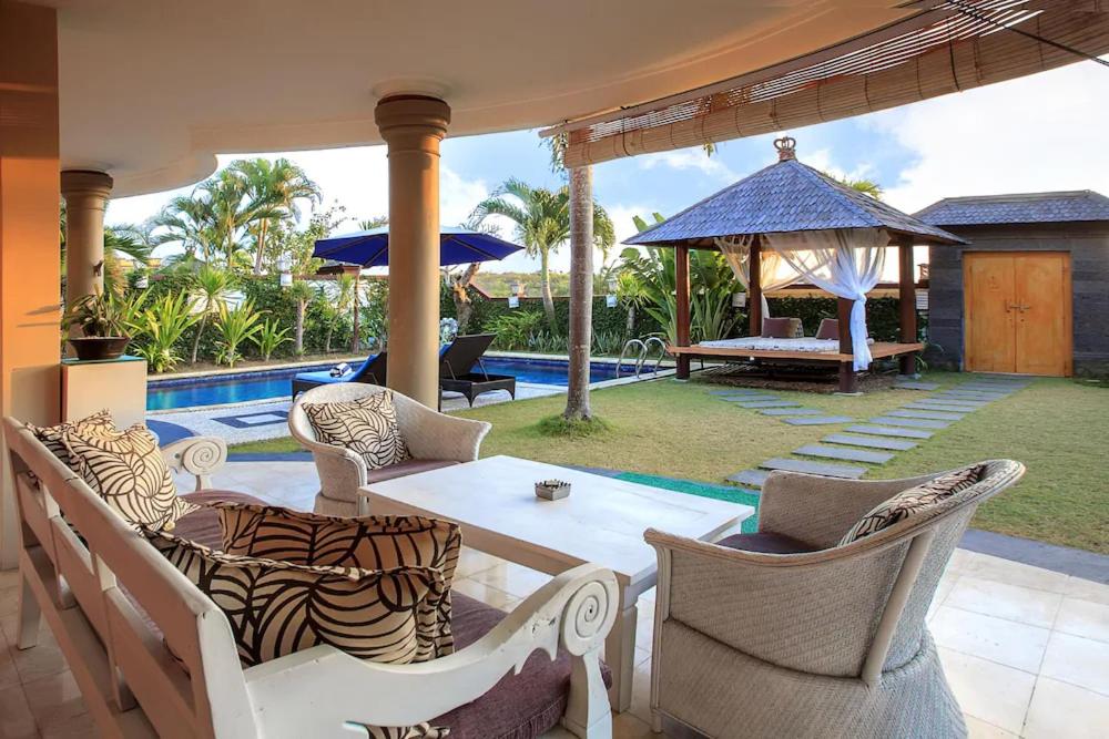a patio with a table and chairs next to a pool at The Beverly Hills Bali Villas Resort in Jimbaran