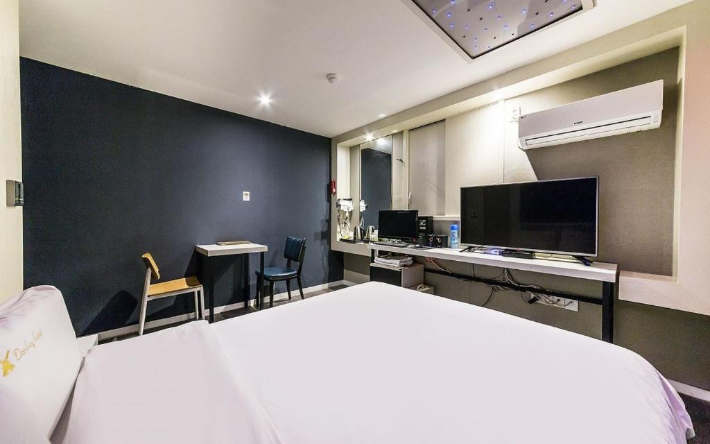 a bedroom with a bed and a desk and a television at Donkey Hotel in Bucheon