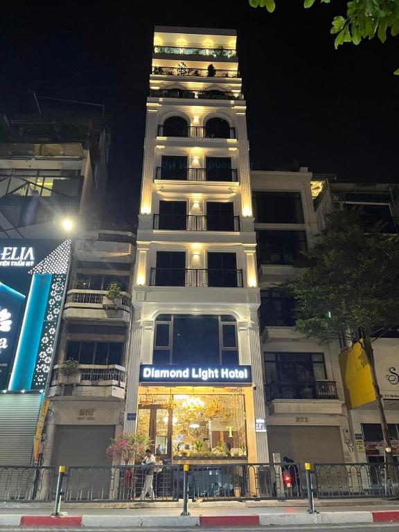 ein hohes weißes Gebäude mit einem Laden davor in der Unterkunft Diamond Light Hotel in Hanoi
