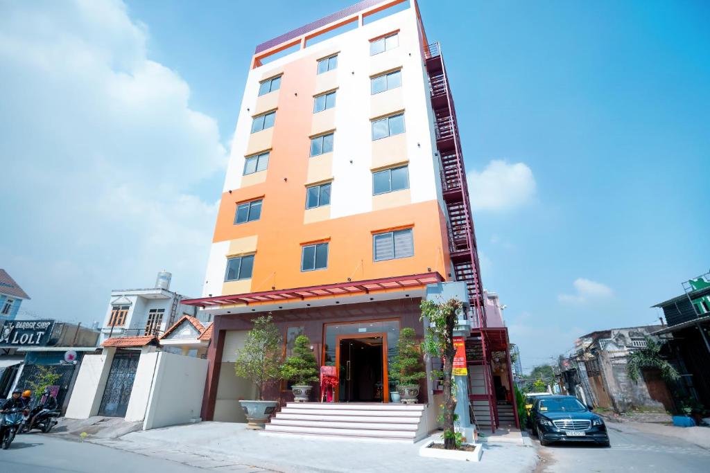 a tall orange and white building on a street at Khách sạn Mona in Dĩ An