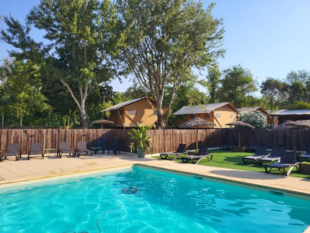 a swimming pool with chairs and a fence at Camping Le Val de Cesse in Mirepeisset