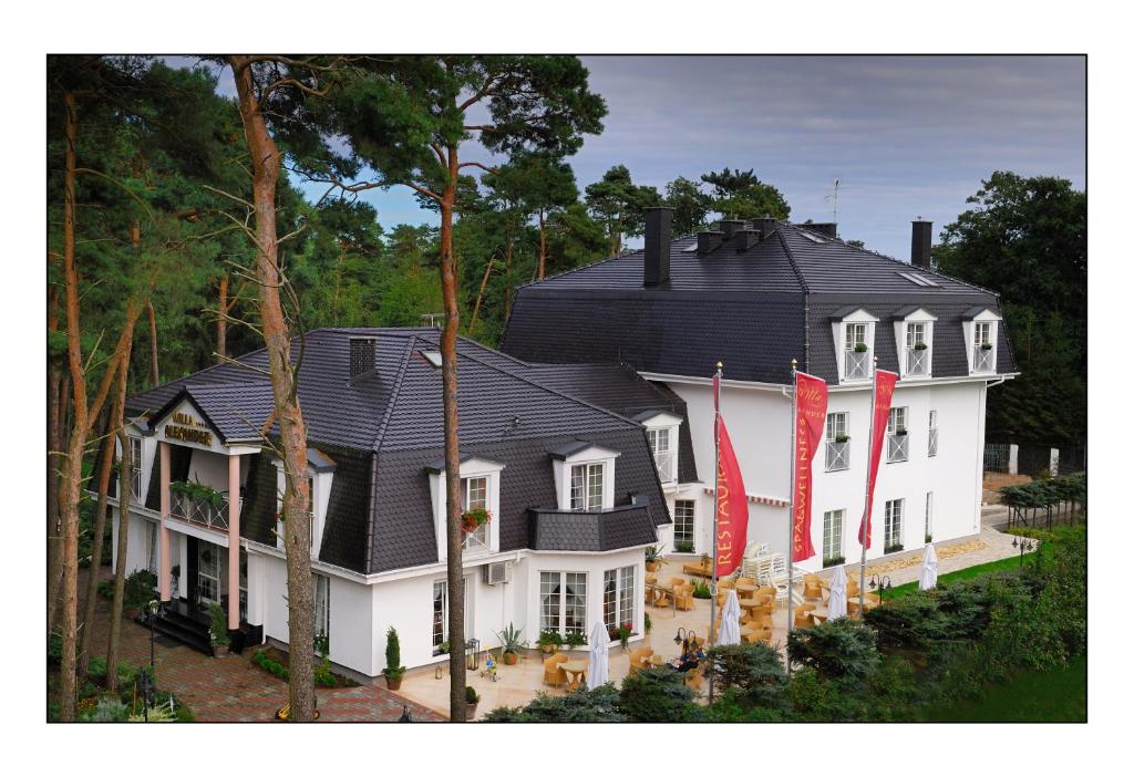 a large white house with red flags in front of it at Willa Alexander Resort & SPA - caloroczny kryty BASEN in Mielno