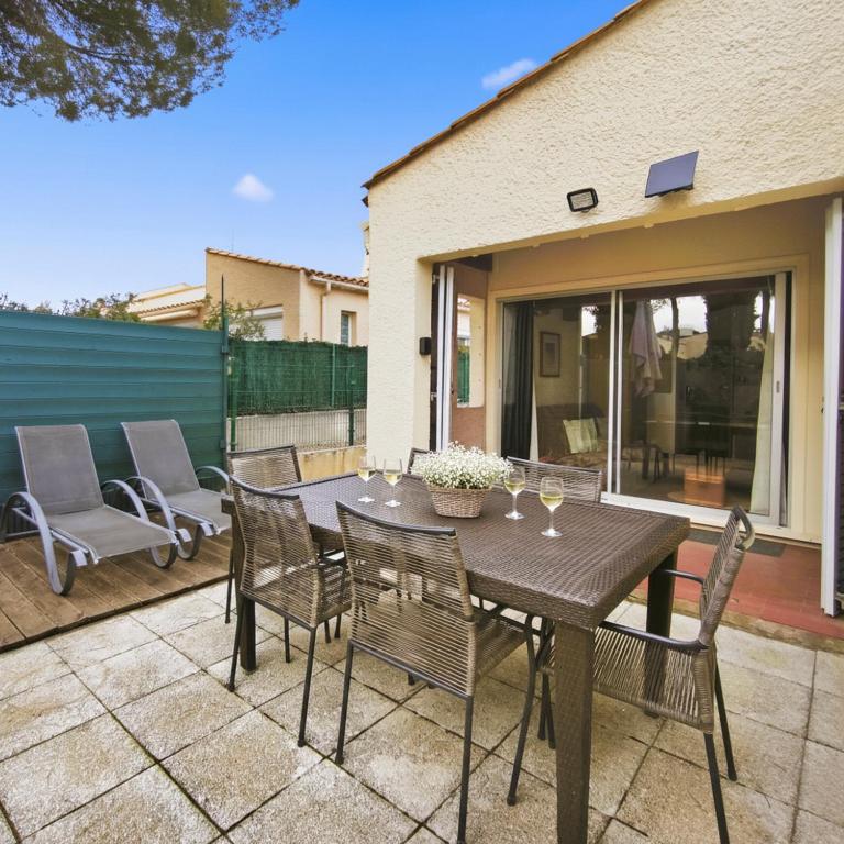 a wooden table and chairs on a patio at Studio Cosy avec terrasse et parking privé in Cap d'Agde
