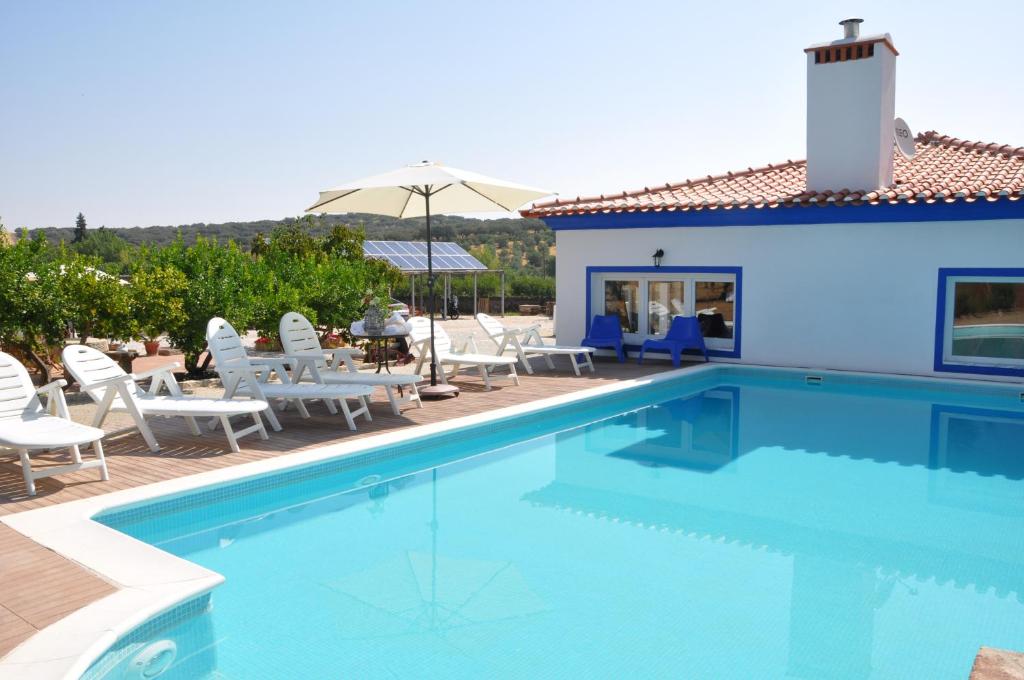 a swimming pool with chairs and a house at Quinta da Sardinha in Elvas