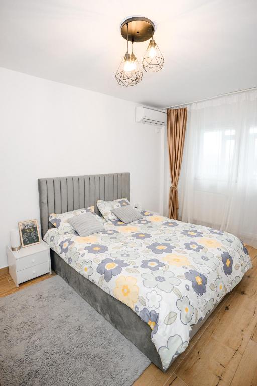 a bedroom with a bed with a floral comforter at Sunset Studio Valcea in Râmnicu Vâlcea