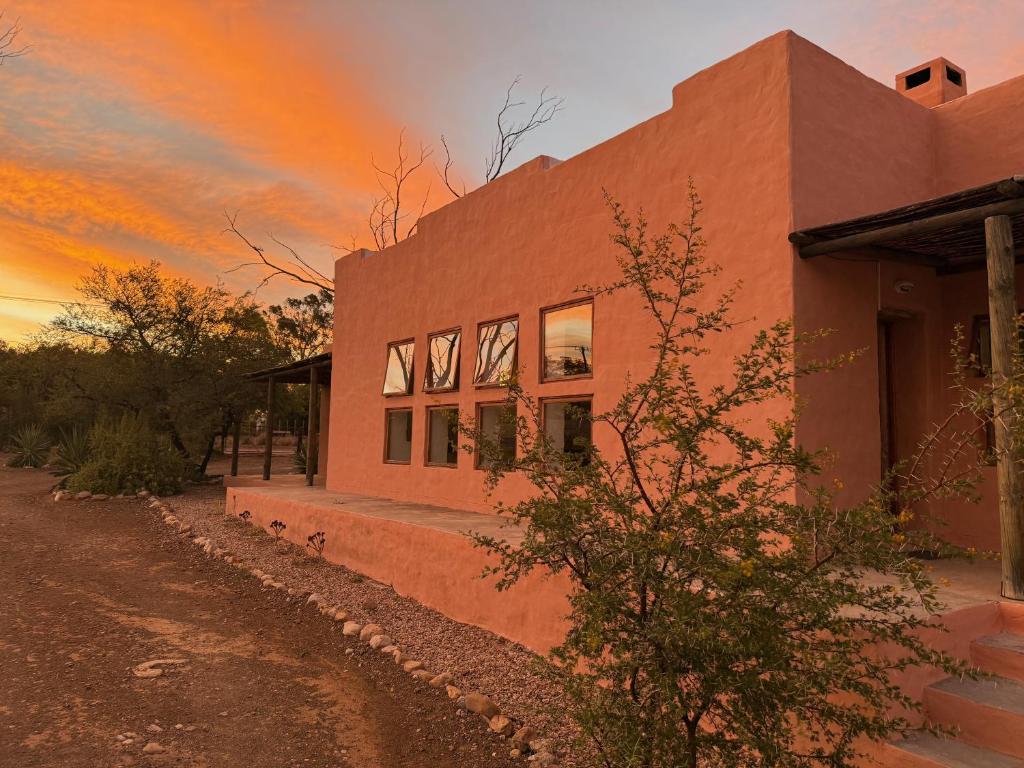 a building in the desert with a sunset in the background at AGAVE HOUSE in Prince Albert