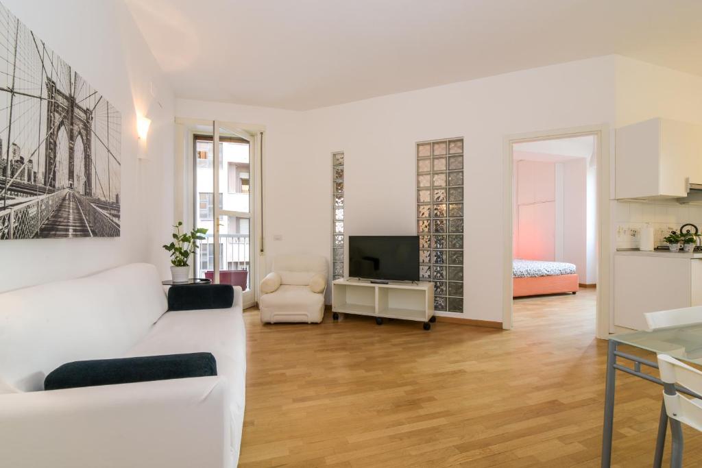 uma sala de estar com um sofá branco e uma televisão em The Best Rent - Fiera Milano City Apartment em Milão