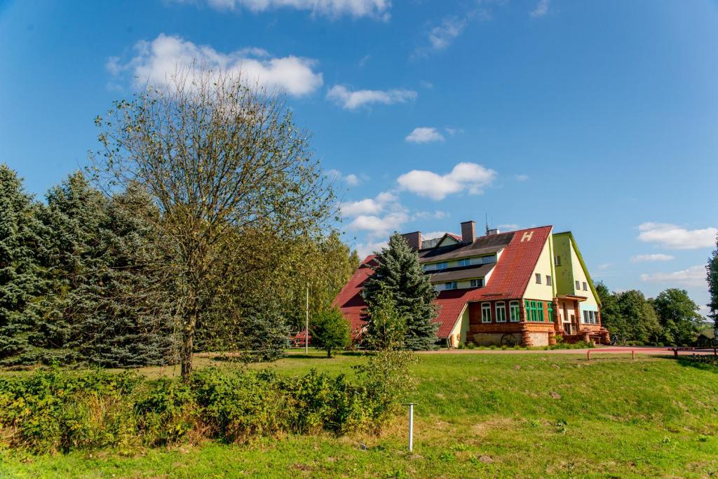 a large house with a red roof on a green field at Park Inn Resort in Mirosławiec