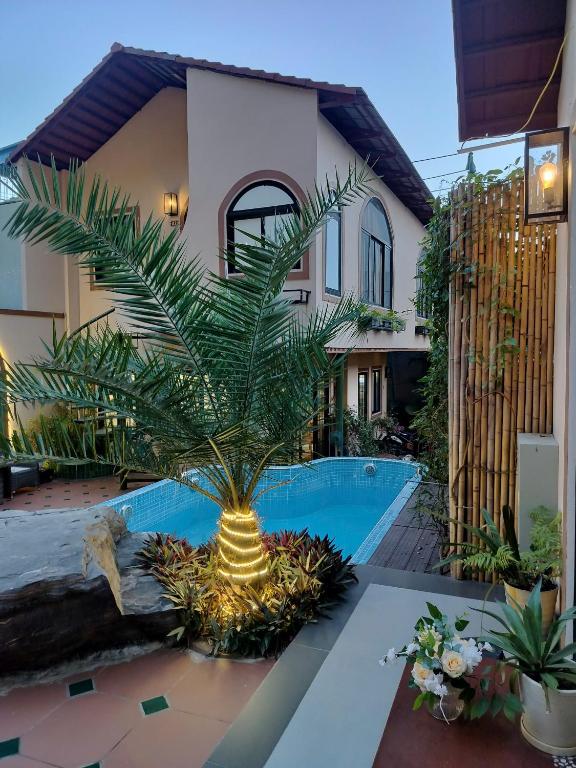 a palm tree in front of a house with a pool at Catba Garden Camellia in Cat Ba