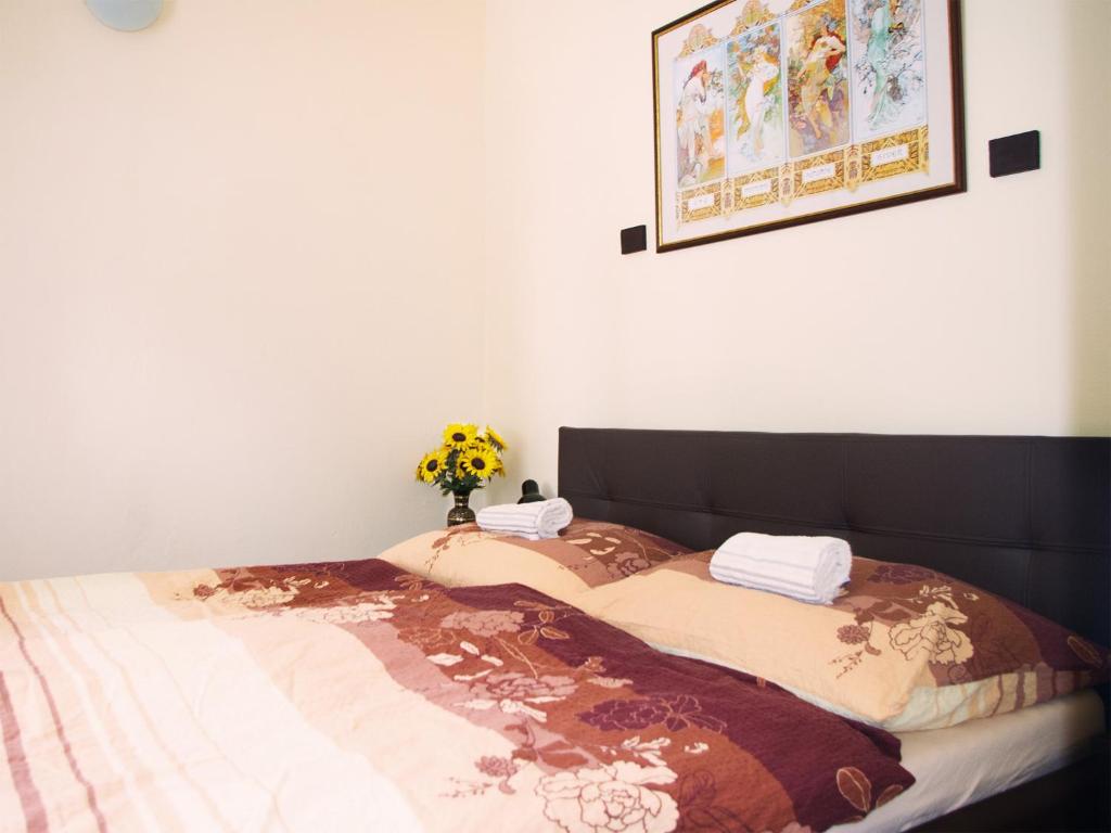Una cama con una manta y un jarrón de flores. en Apartment Sense of Zizkov en Praga