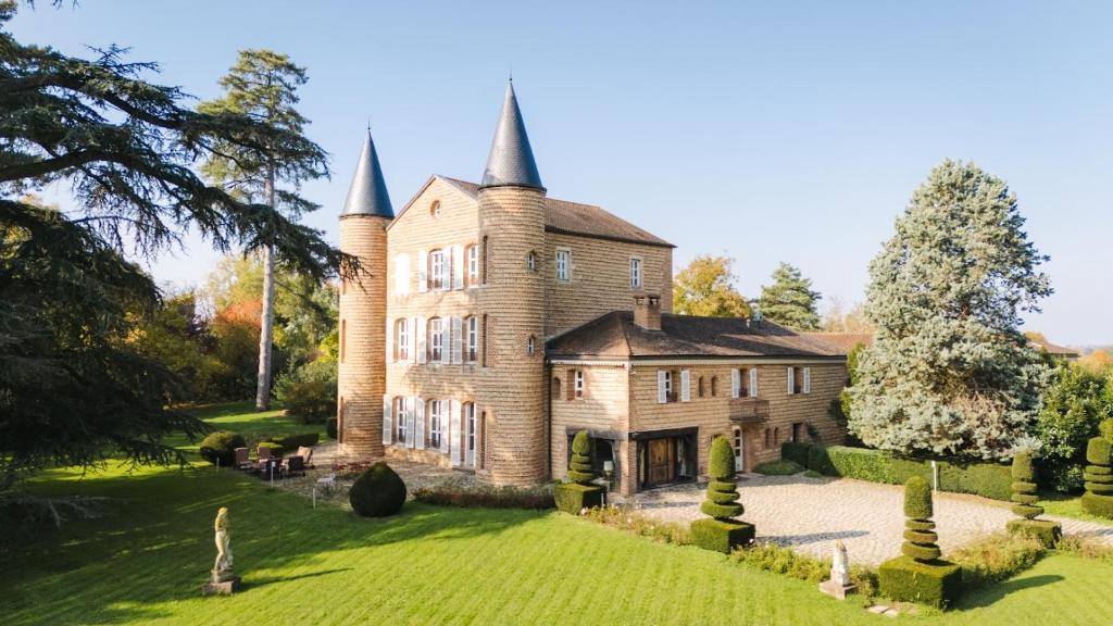 an old stone house with two towers on a lawn at Château de Bissieux in Châtillon-sur-Chalaronne