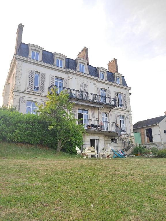 a large house with a table and chairs in front of it at Le Flow de Ginette in La Celle-sous-Gouzon