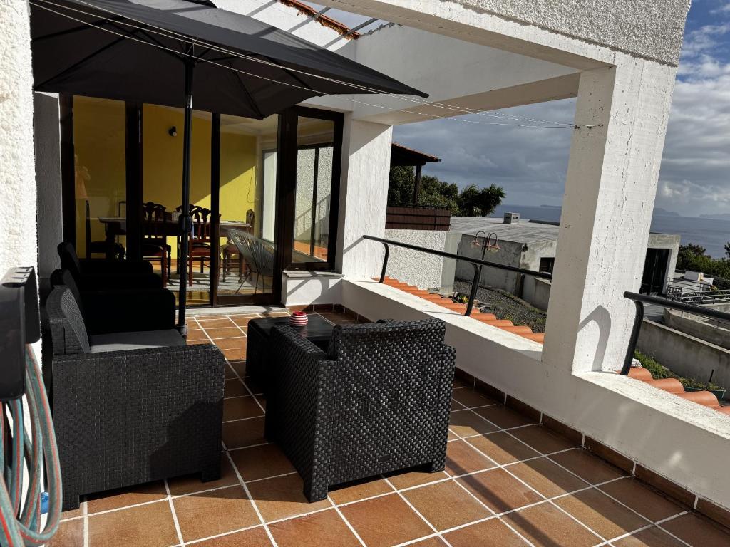 a patio with chairs and an umbrella on a roof at Machico View in Machico